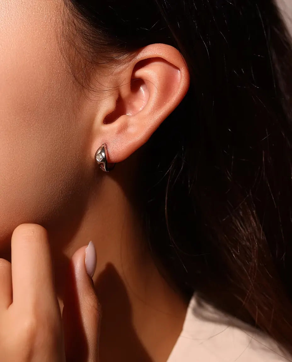 Moissanite Örhängen i 925 Sterlingsilver - burna i en modells öra, handen nära ansiktet