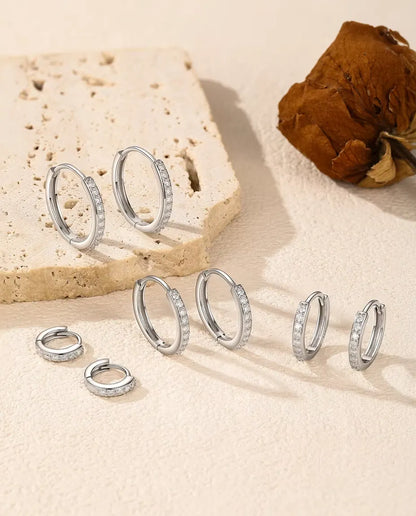 Moissanite Örhängen i 925 Sterlingsilver - alla fem storlekarna på en ljus yta vid en travertinplatta