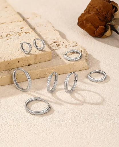 Moissanite Örhängen i 925 Sterlingsilver - fem storlekar utspridda på en travertinplatta och en ljus yta