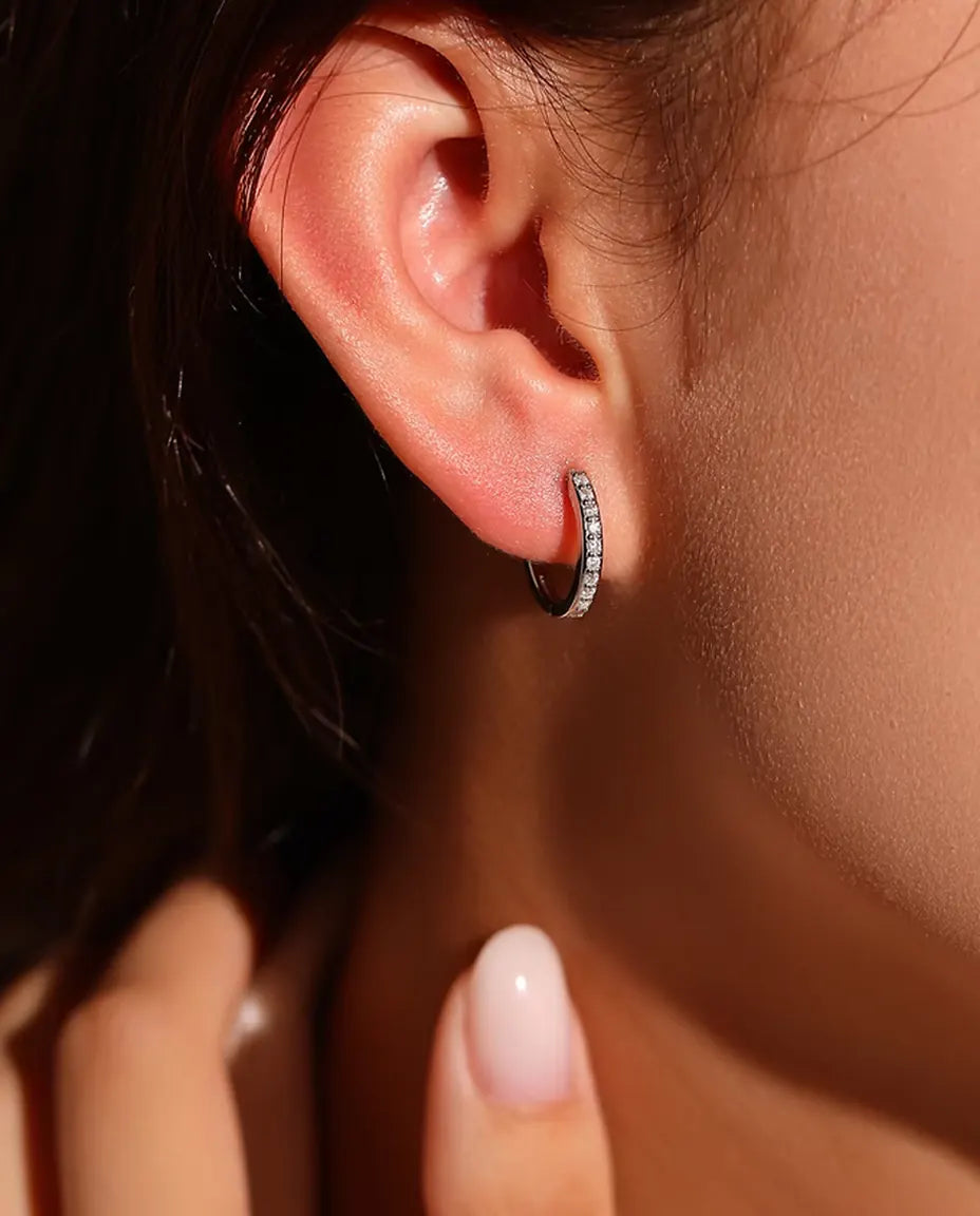 Moissanite Örhängen i 925 Sterlingsilver - burna i en modells öra, handen nära ansiktet