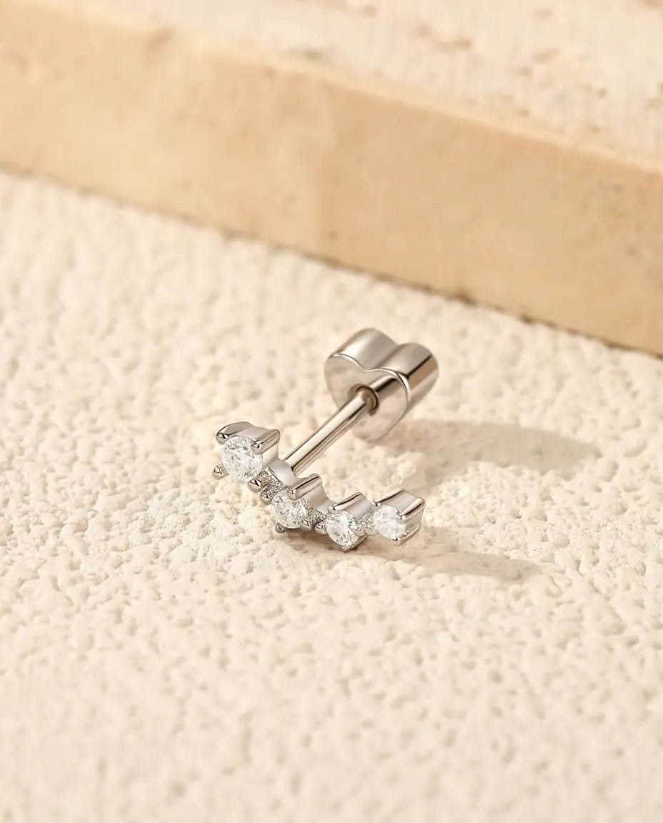Klätterörhängen med Moissanit i 925 Sterlingsilver - på en ljus strukturerad yta bredvid en travertinplatta