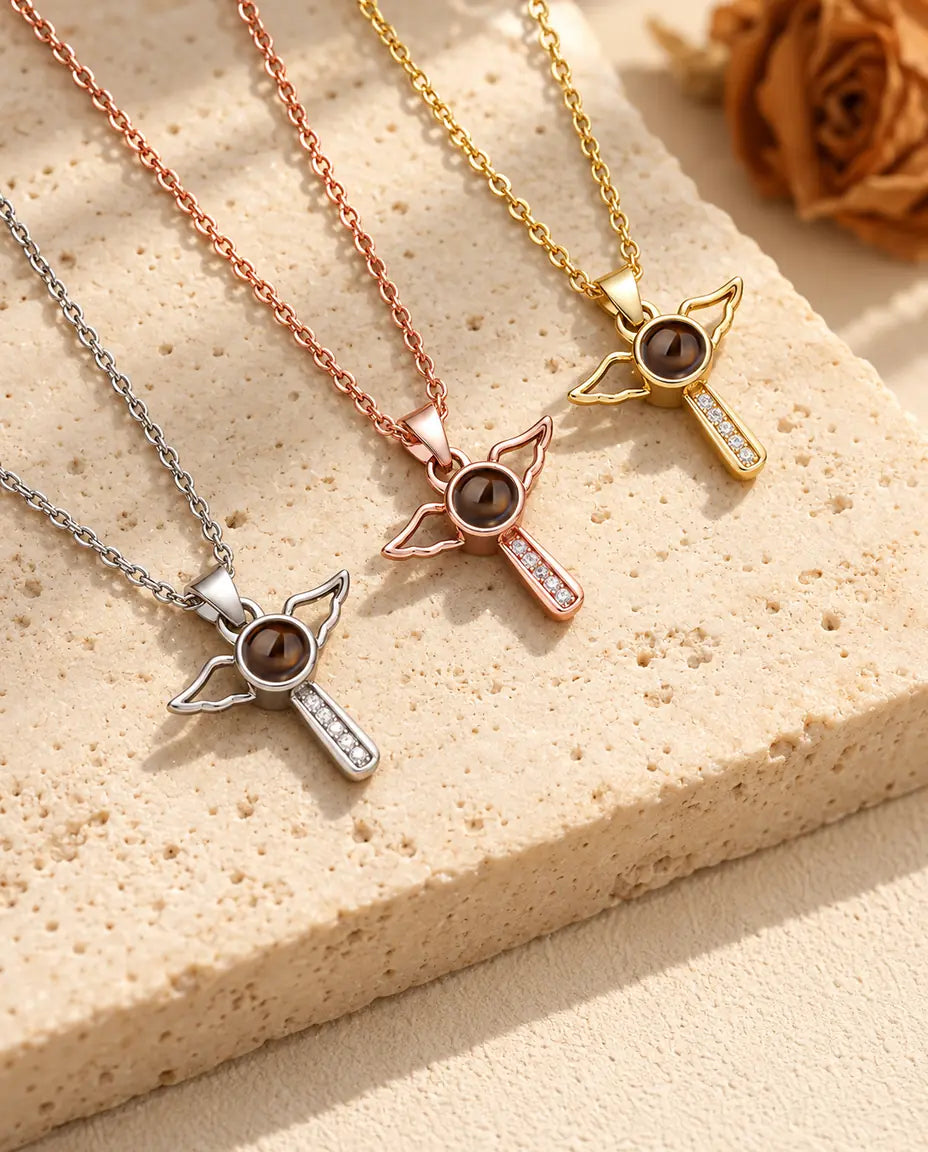 Tre halsband med kors och änglavingar diagonalt lagda bredvid travertin