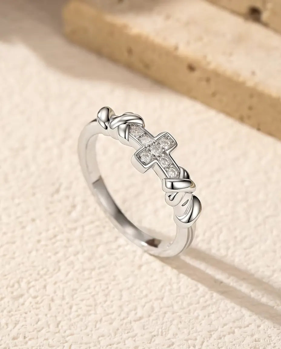 Moissanite Ring med Kors i 925 Sterlingsilver - stående på en ljus strukturerad yta