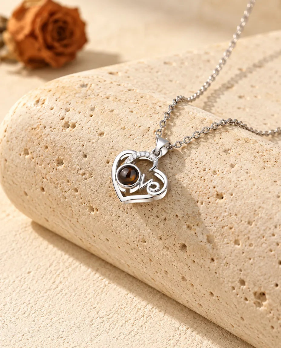 Personligt halsband med bild inuti: ett silverfärgat Love-hjärta med en båge av zirkonia, lutat mot ett travertinblock