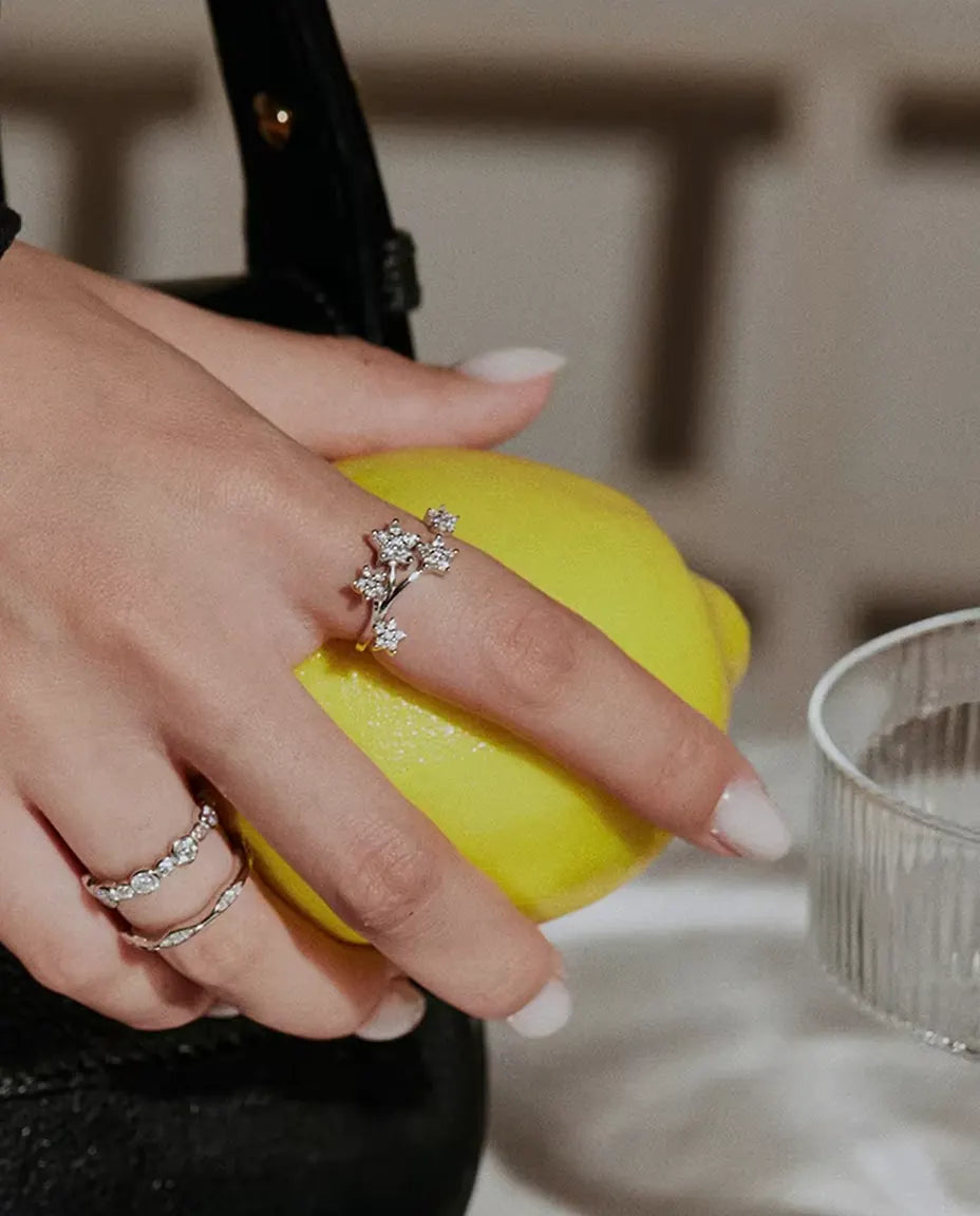 Öppen Moissanite Ring med Stjärnor i 925 Sterlingsilver - buren tillsammans med andra ringar, handen håller en citron