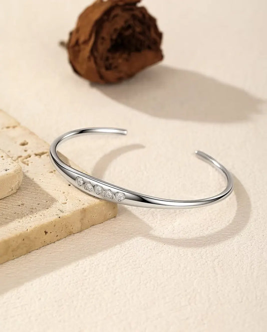 Öppet Moissanite Armband i 925 Sterlingsilver - draperat över en travertinplatta