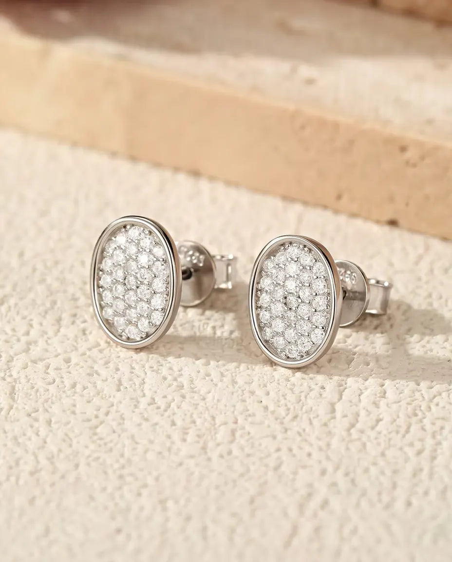 Ovala Stiftörhängen med Pavéfattade Moissaniter i 925 Sterlingsilver - paret på en ljus strukturerad yta