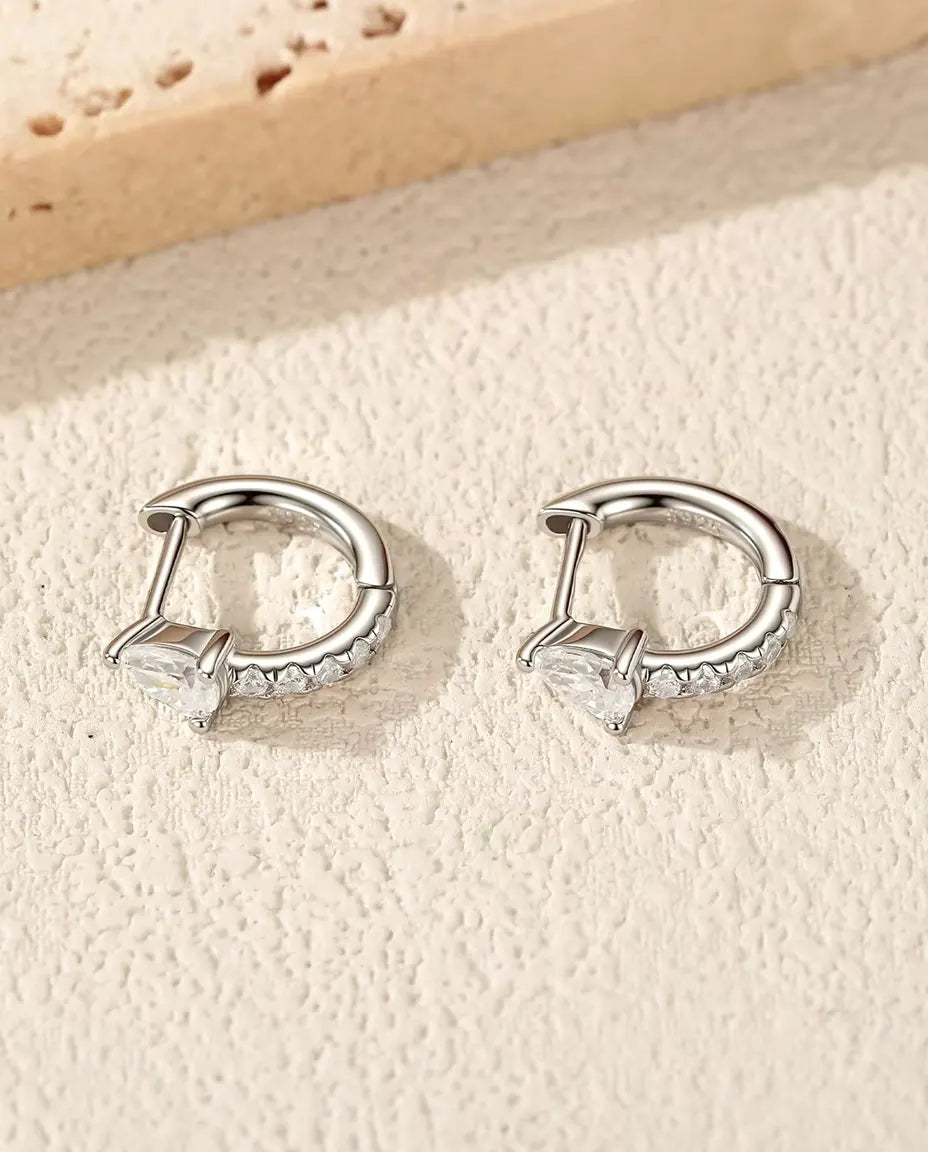 Små Creoler med Droppslipad Moissanit i 925 Sterlingsilver - paret på en ljus strukturerad yta