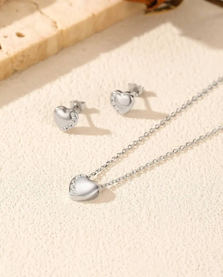 Smyckeset med Hjärta i 925 Sterlingsilver - halsband och örhängen tillsammans på en ljus strukturerad yta