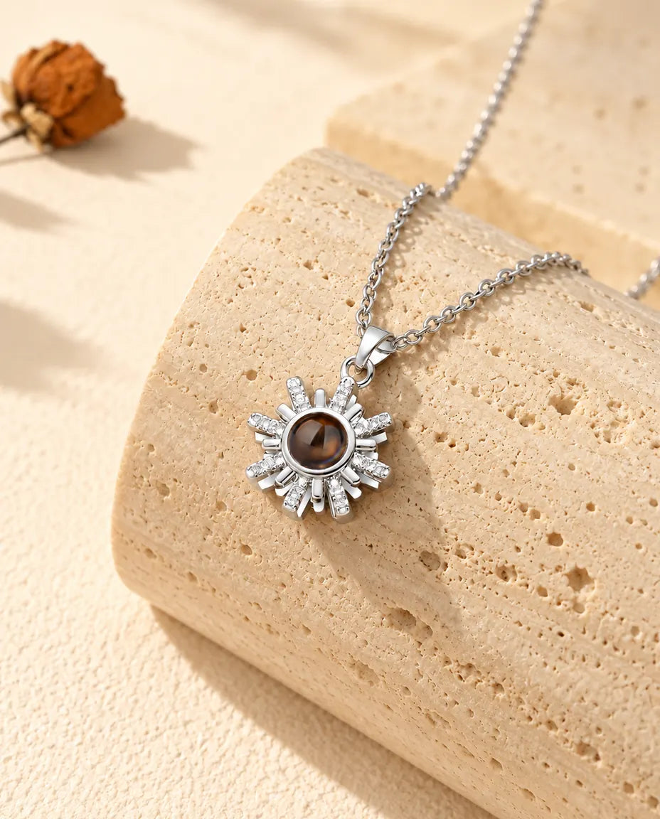 Silverfärgat solhalsband med bild inuti, hängande över travertin