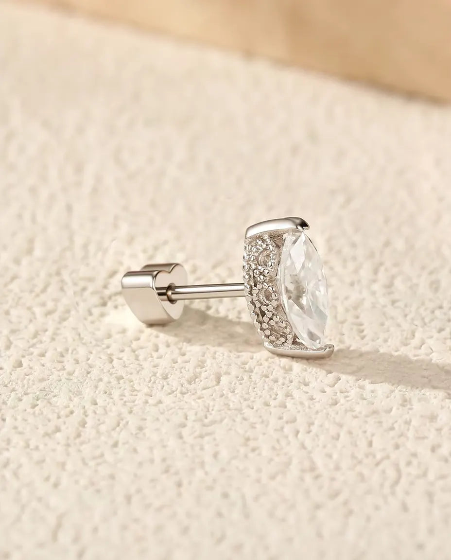 Stiftörhängen med Markisslipad Moissanit i 925 Sterlingsilver - på en ljus strukturerad yta bredvid en travertinplatta