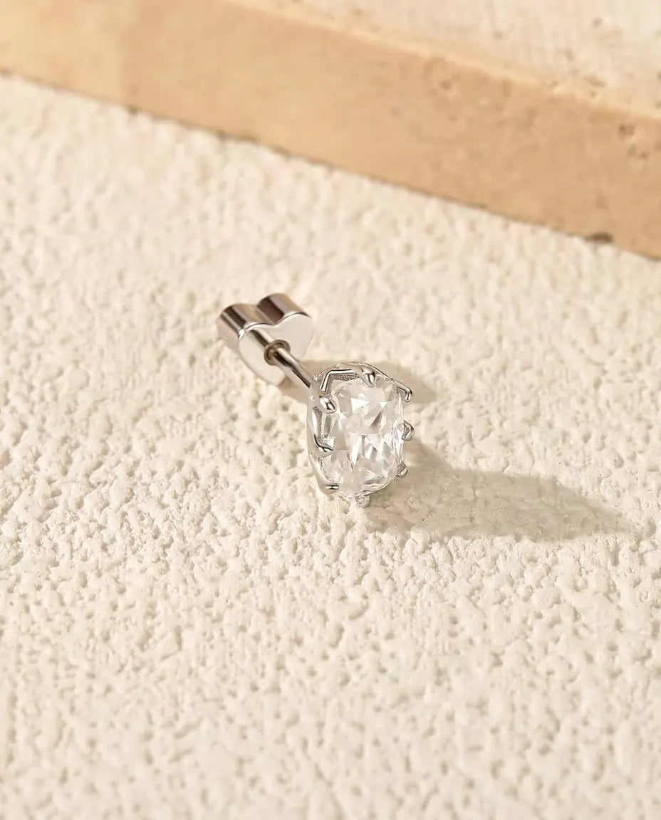 Stiftörhängen med Radiantslipad Moissanit i 925 Sterlingsilver - på en ljus strukturerad yta bredvid en travertinplatta