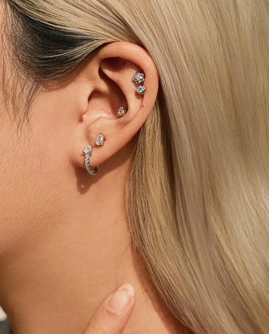 Stiftörhängen med Droppslipad Moissanite och Två Klor i 925 Sterlingsilver - buret av en modell med handen vid halsen