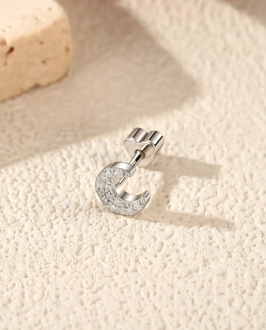 Stiftörhängen med Månskära i Pavé av Moissaniter i 925 Sterlingsilver - liggande på sidan på en ljus strukturerad yta, hjärtformat lås på stiftet