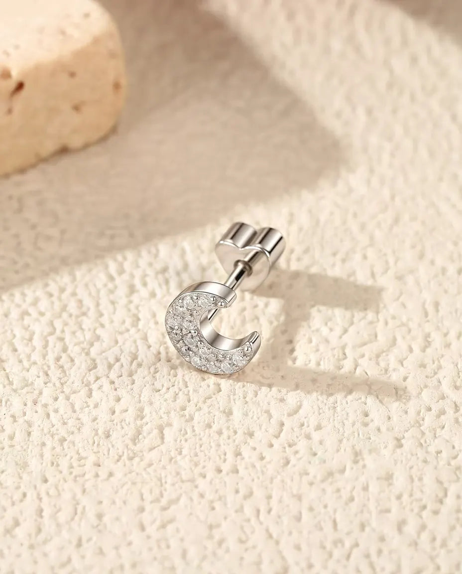 Stiftörhängen med Månskära i Pavé av Moissaniter i 925 Sterlingsilver - liggande på sidan på en ljus strukturerad yta, hjärtformat lås på stiftet