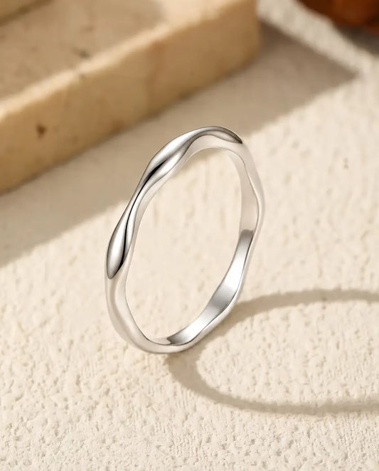 Vågig Ring i 925 Sterlingsilver - stående på en ljus strukturerad yta