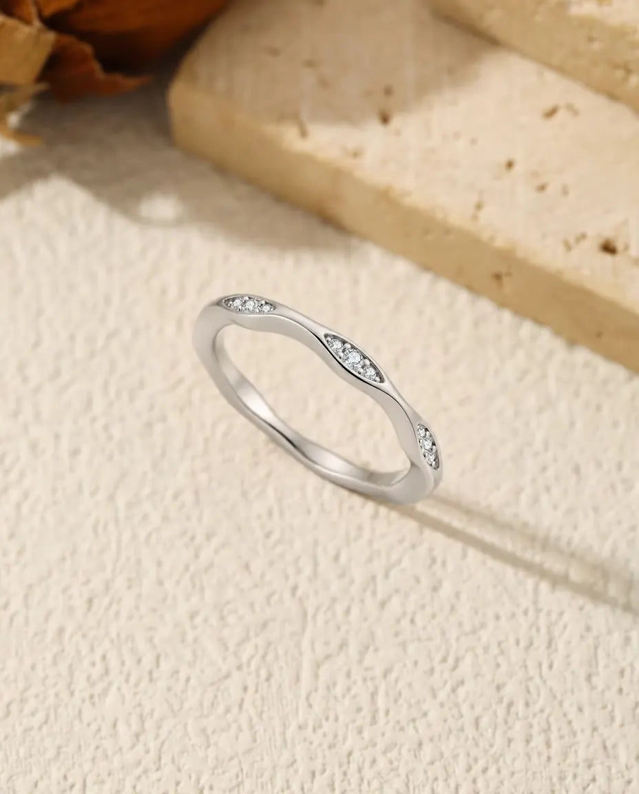 Vågig Moissanite Ring i 925 Sterlingsilver - stående på en ljus strukturerad yta
