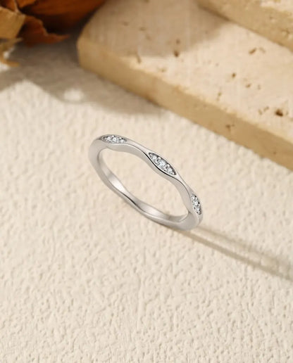 Vågig Moissanite Ring i 925 Sterlingsilver - stående på en ljus strukturerad yta