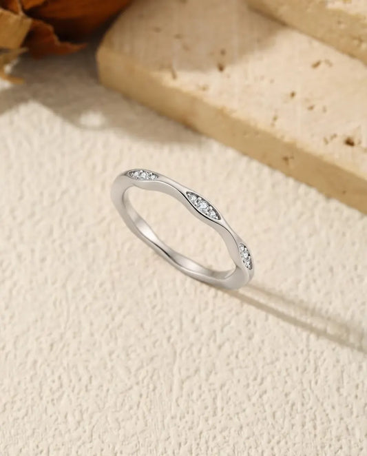 Vågig Moissanite Ring i 925 Sterlingsilver - stående på en ljus strukturerad yta